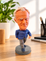 Figurka bobblehead na biurku z etykietą AI.png